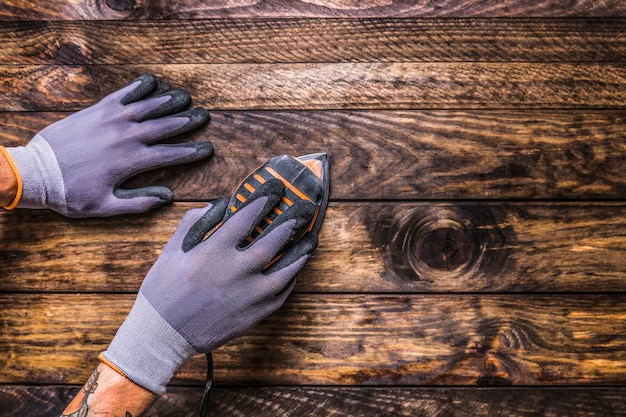 Free Photo elevated view of carpenter's hand using sanding machine on wooden background