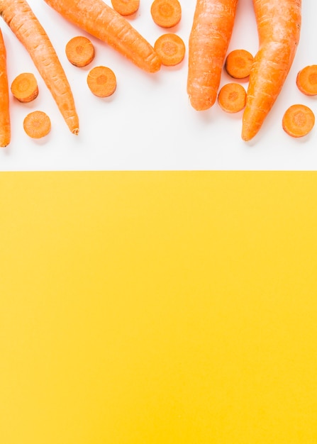 Free photo elevated view of carrots on dual white and yellow background