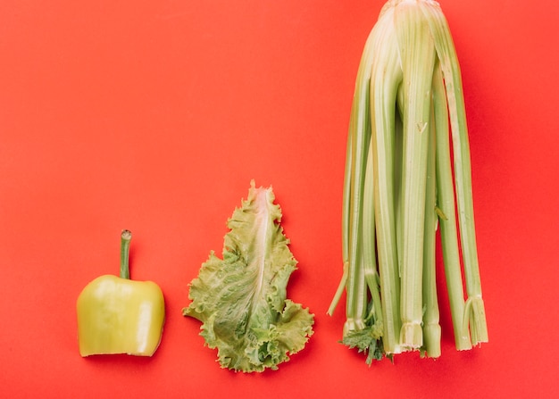 Free photo elevated view of chard; lettuce and green bell pepper on red backdrop