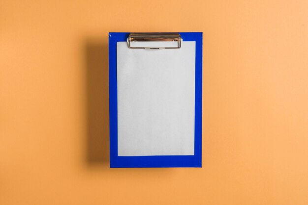 Elevated view of clipboard with blank paper on colored background