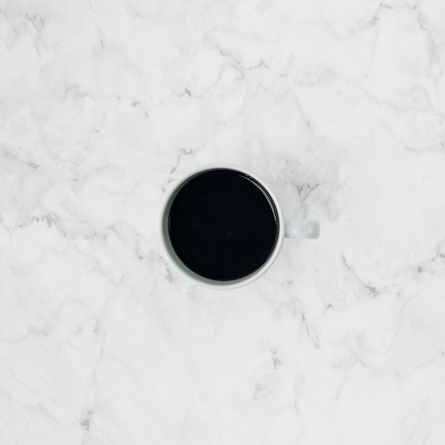 An elevated view of coffee cup over the marble textured backdrop