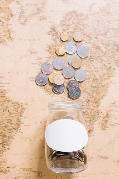 Free Photo elevated view of coins over the open jar on world map