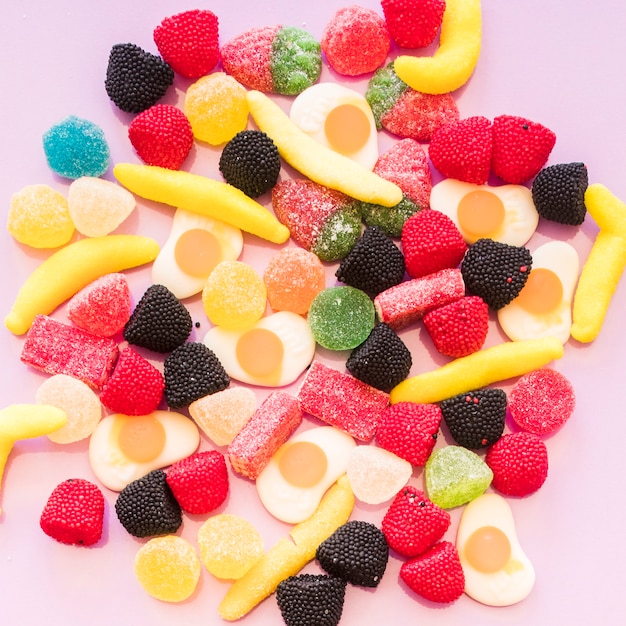 Free photo elevated view of colorful jelly and gummy sugar candies on pink background