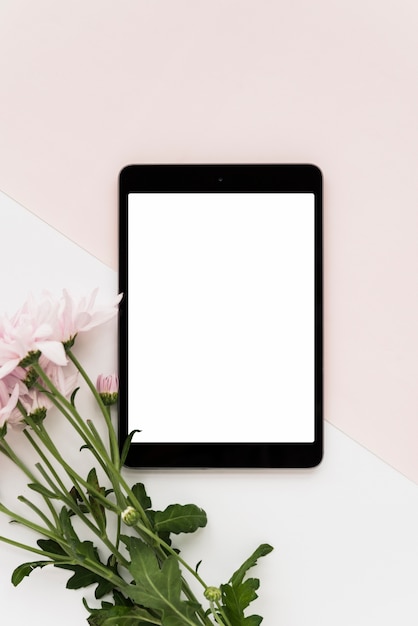 Free photo elevated view of digital tablet and fresh flowers on dual background