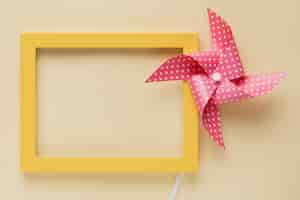 Free photo elevated view of dotted pinwheel and yellow frame on beige background