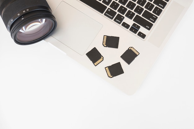 Elevated view of dslr camera and memory cards on laptop keyboard