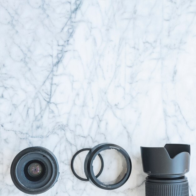 Elevated view of dslr camera with lens and extension rings on marble background