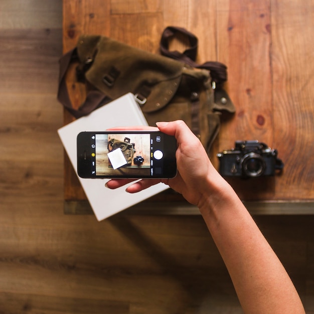 Free Photo elevated view of female hand taking photo of bag and notebook on table