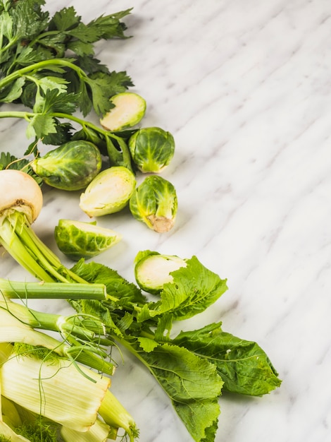 Free photo elevated view of fresh green vegetables on marble background