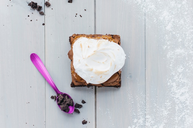 Elevated view of fresh pastry with chocolate on spoon over wooden plank