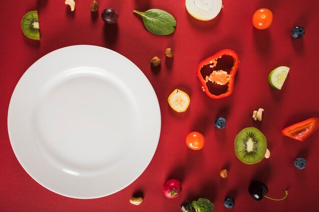 Elevated view of fresh raw food with plate on red background