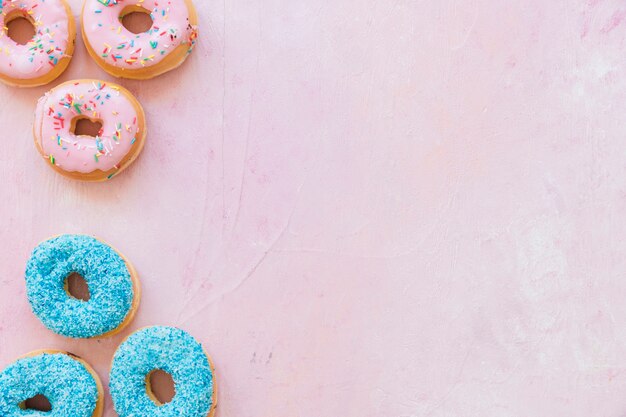 Elevated view of fresh tasty donuts on pink backdrop