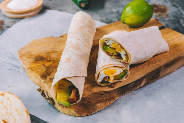 Free photo elevated view of garnished delicious mexican nachos in plate with wrap tacos on cutting board