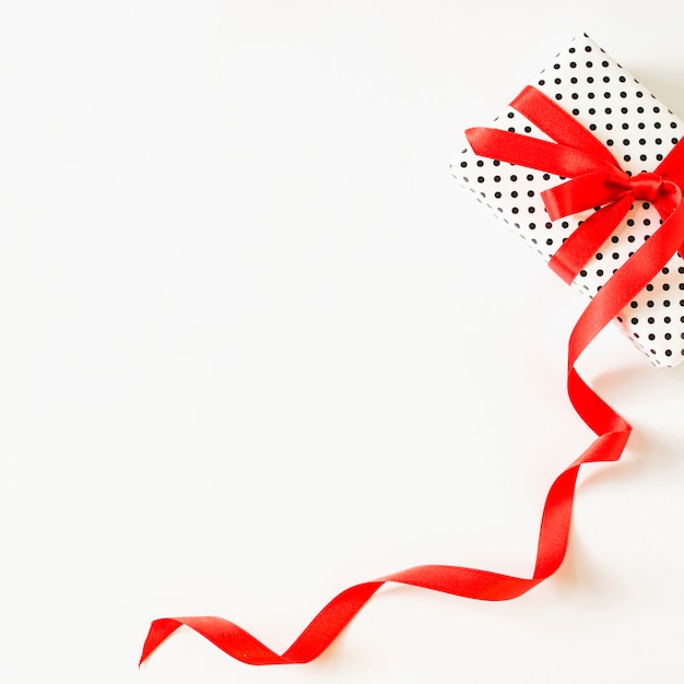 Free photo elevated view of gift tied with red ribbon on white surface