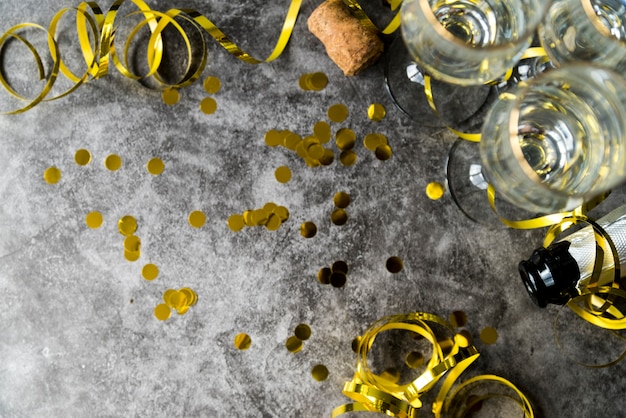 Free photo elevated view of golden confetti and streamers with empty glass over concrete textured