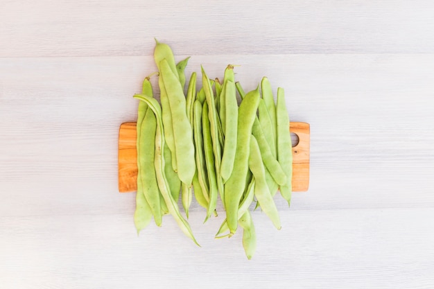 Free photo elevated view of green hyacinth beans on wooden cutting board