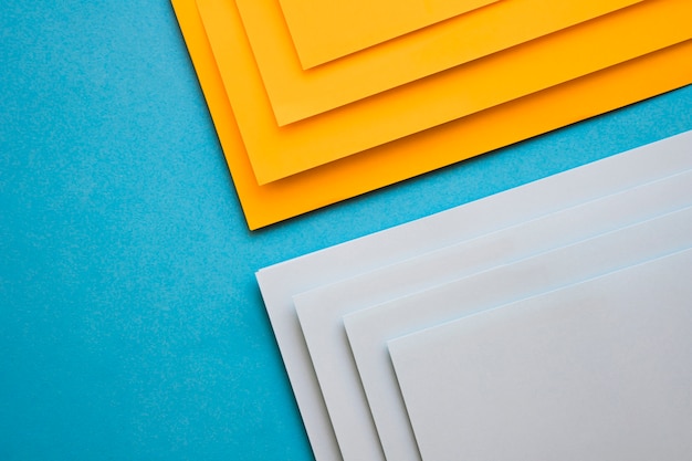 Elevated view of grey and yellow cardboard papers on blue surface