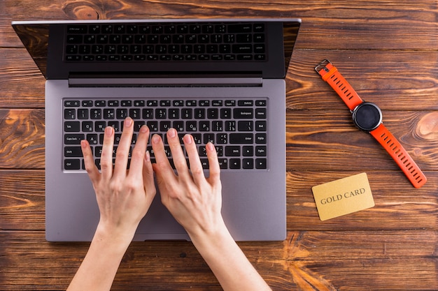 Free photo elevated view of hand typing on laptop over wooden table