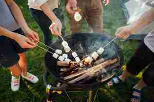 Free photo elevated view of hands roasting marshmallow on barbecue fire