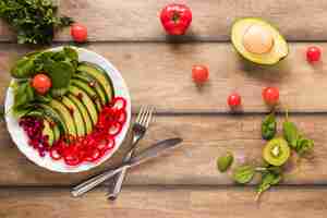 Free photo elevated view of healthy vegetable and fruit salad in white plate on wooden table