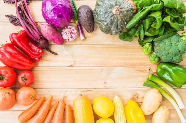 Elevated view of healthy vegetables forming circular frame on wooden backdrop