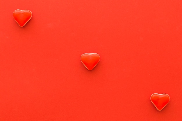 Free photo elevated view of heart shape candies on red background