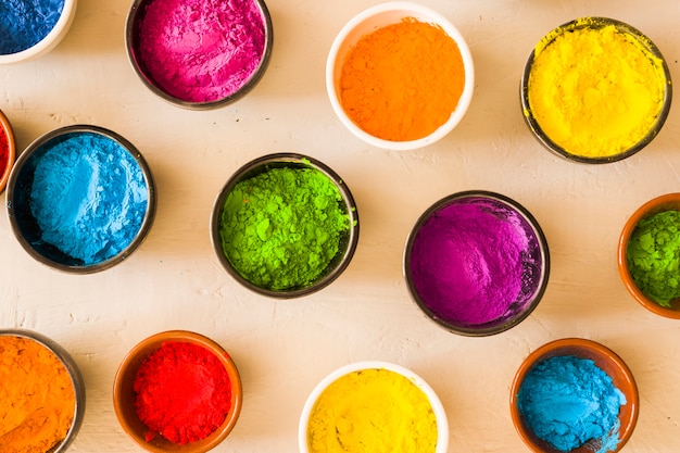 Free photo an elevated view of holi color powder in the different type of bowls on concrete backdrop