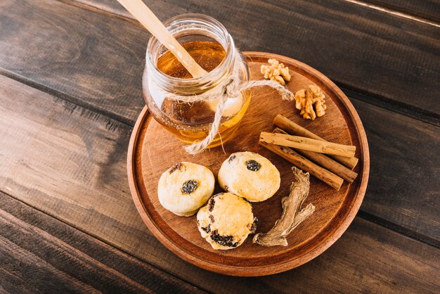 Elevated view of honey; walnut; cinnamon; cup cakes and ginger on wooden board