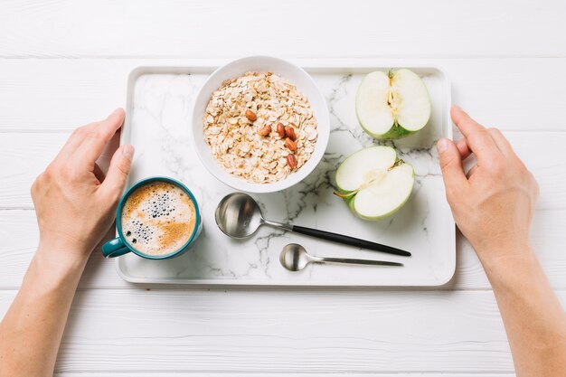 Elevated view of human hands holding tray of tasty meal over white background