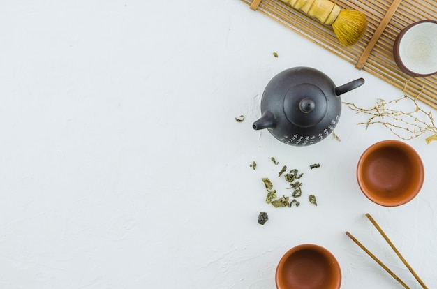 An elevated view of japanese herbal tea with tea set on white background