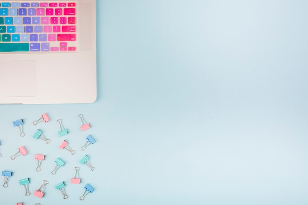 Free photo elevated view of laptop and bulldog clips on blue background