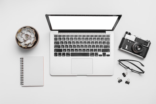 Elevated view of a laptop and retro camera isolated on white background