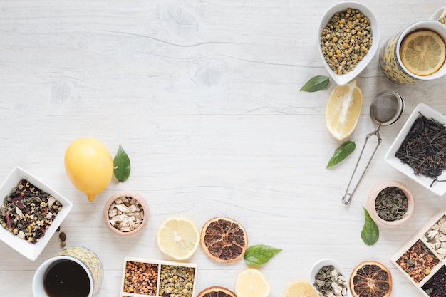 Elevated view of lemon tea; herbs; strainer; dried chinese chrysanthemum flowers and dry grapefruit