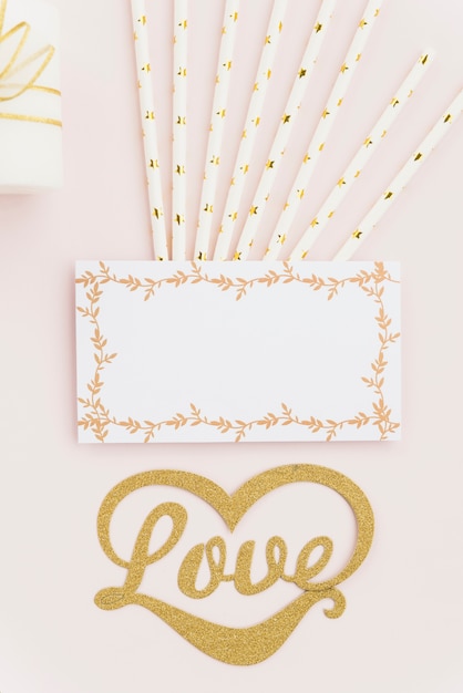 Free Photo elevated view of love text with drinking straws and blank white card on colored backdrop