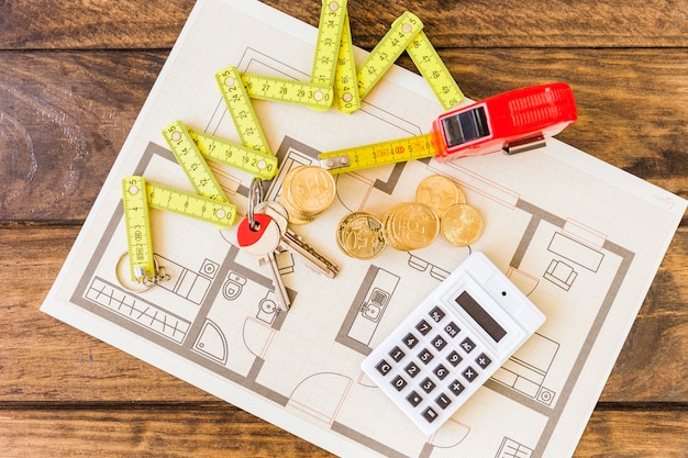 Free Photo elevated view of measure tape, stacked coins, key and calculator on blueprint