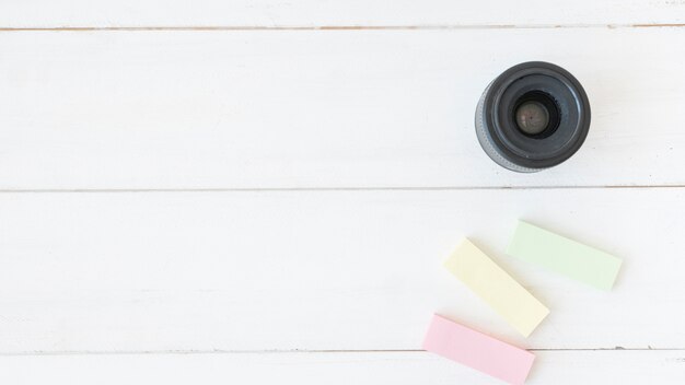 Free Photo elevated view of modern camera lens with colorful sticky notes on wooden table