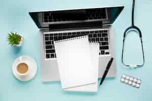 Free photo elevated view of notepad on laptop near coffee cup and succulent plant over medical desk