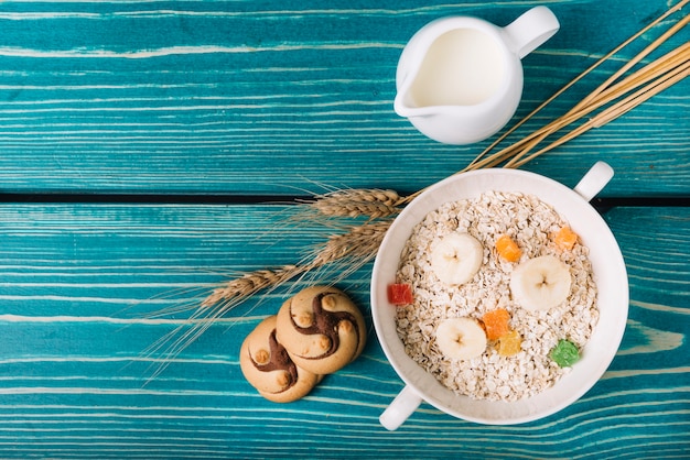 Elevated view of oatmeal with milk and cookies on table