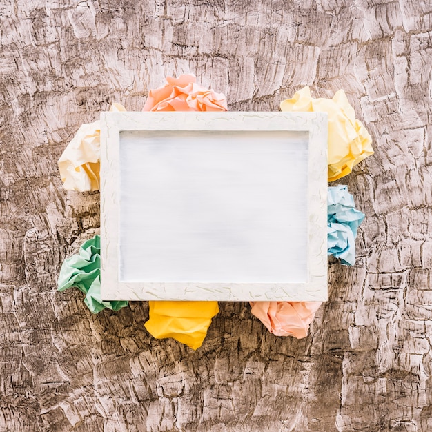 Free photo elevated view of picture frame over multi colored crumpled paper