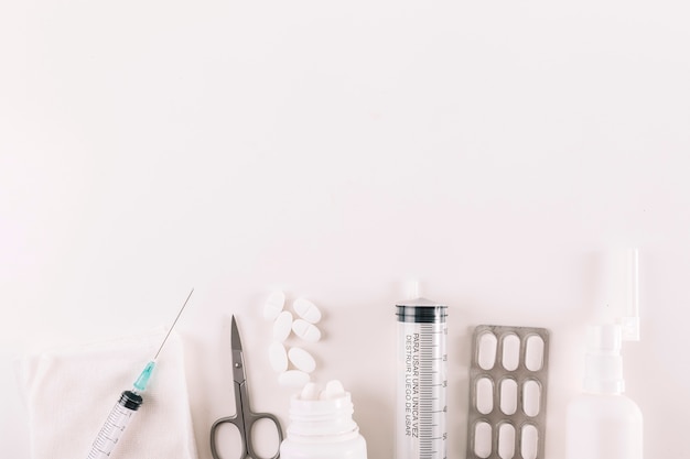 Elevated view of pills and medical equipments on white background