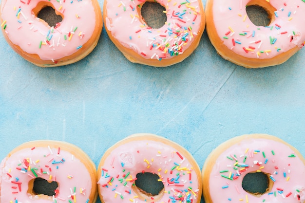 Free photo elevated view of pink donuts in a row on blue background