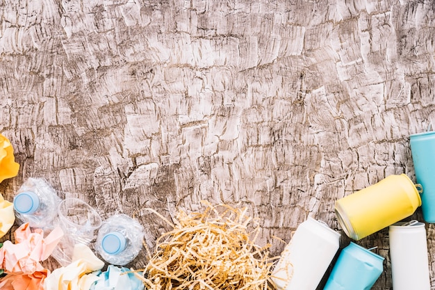 Elevated view of plastic bottles, crumpled papers and tin cans on wooden surface