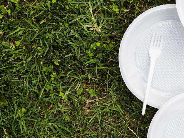 Free photo elevated view of plastic plate and fork on grass at park