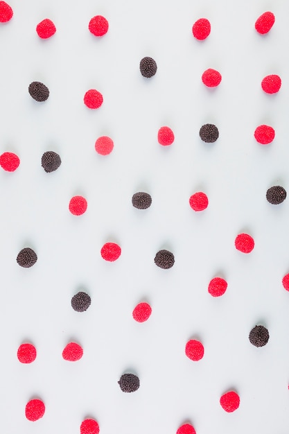 Free Photo elevated view of red and black cranberry candies on colored background