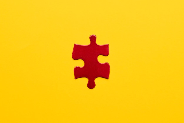 Free Photo elevated view of red jigsaw puzzle piece on yellow backdrop