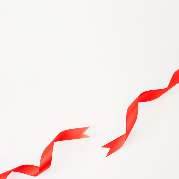 Elevated view of red satin ribbons on white backdrop