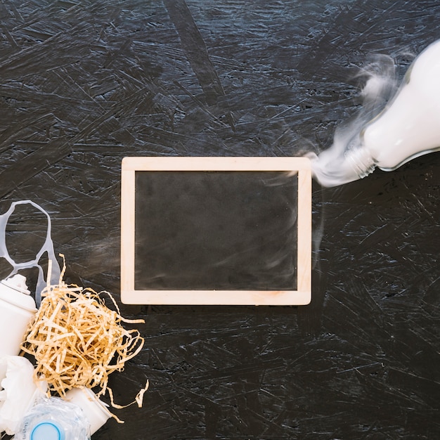 Free photo elevated view of slate with smoke coming out from light bulb