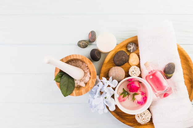 Free Photo elevated view of spa stones; salt; towel; flowers and oil on white background