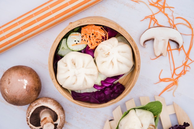 Free photo an elevated view of steam dumplings and salad in bamboo steamer