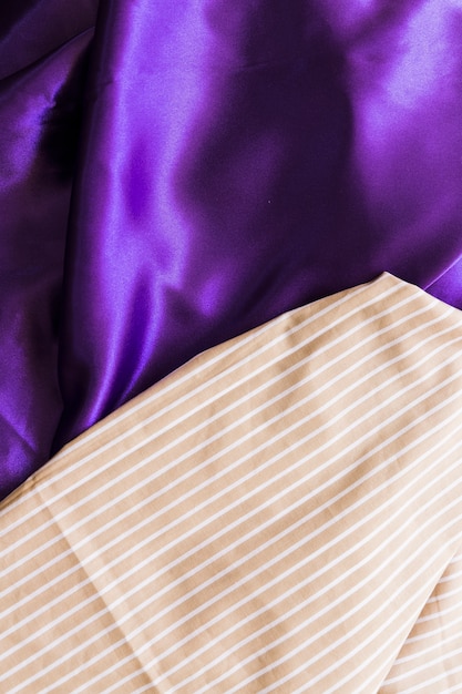 Elevated view of straight line pattern textile on silky purple drape